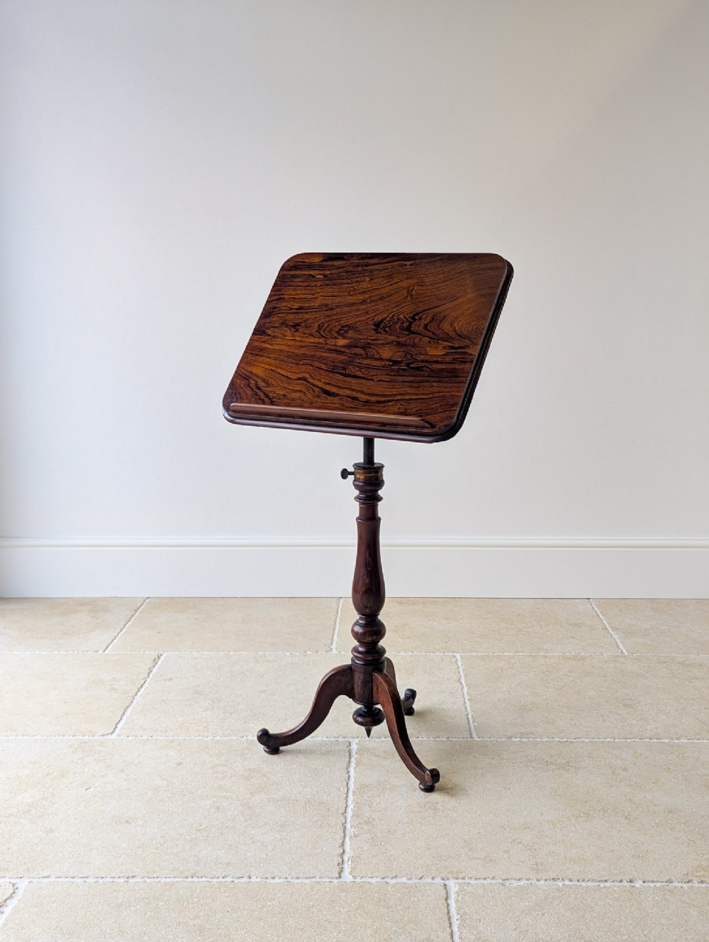 An antique William IV rosewood reading stand featuring a rectangular tilted top on an adjustable turned pedestal with a tripod base.