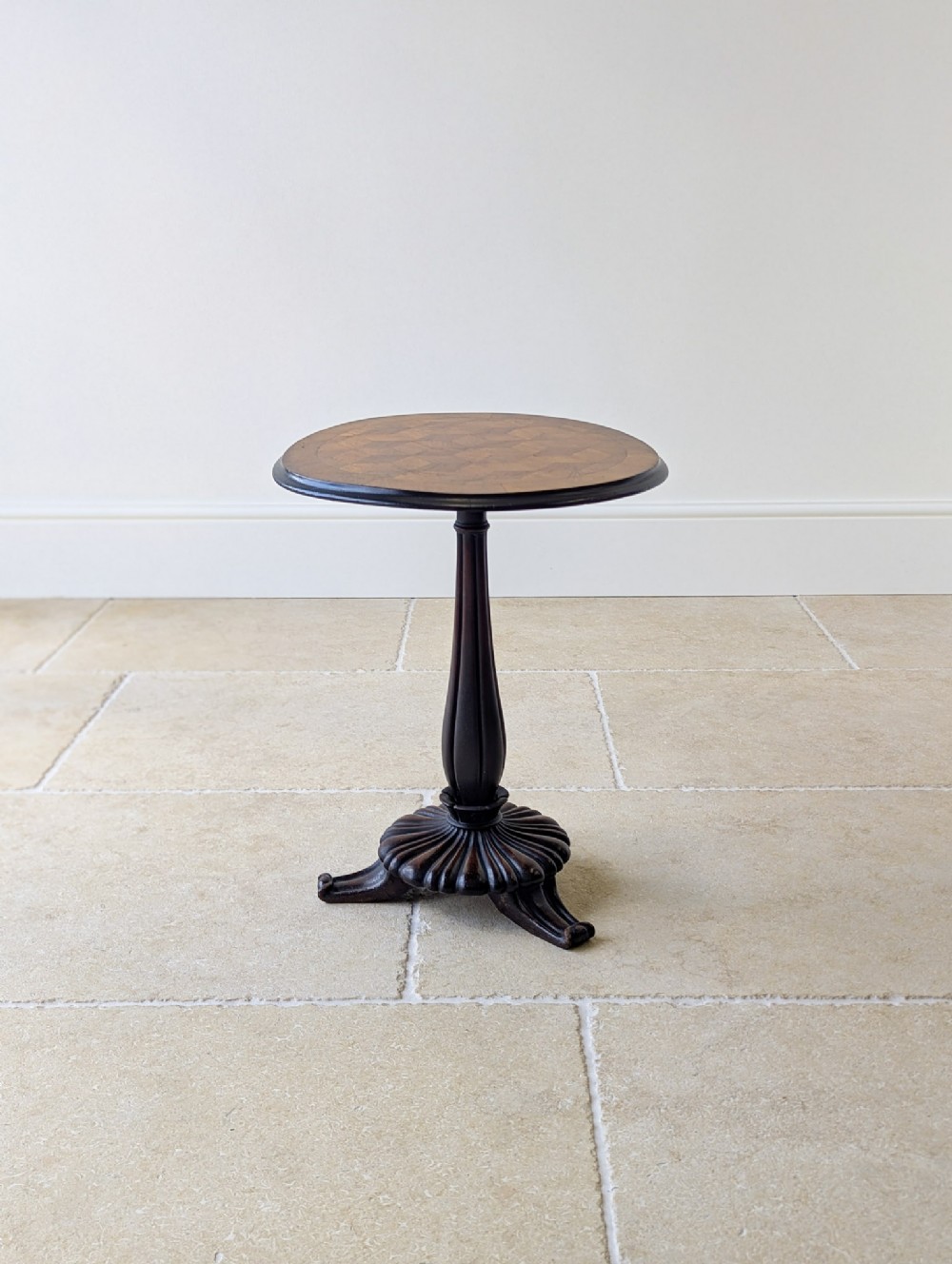 An antique William IV walnut and mahogany wine table featuring a circular top with decorative marquetry, a fluted column, and a carved tripod base.
