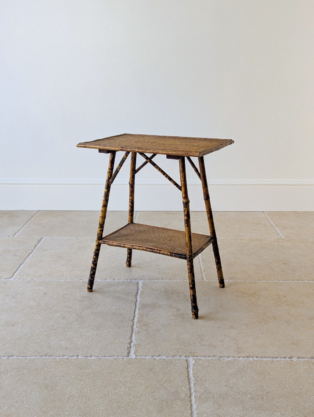 An antique Victorian bamboo occasional table featuring a rectangular woven rattan top, a lower tier shelf, and splayed mottled bamboo legs.