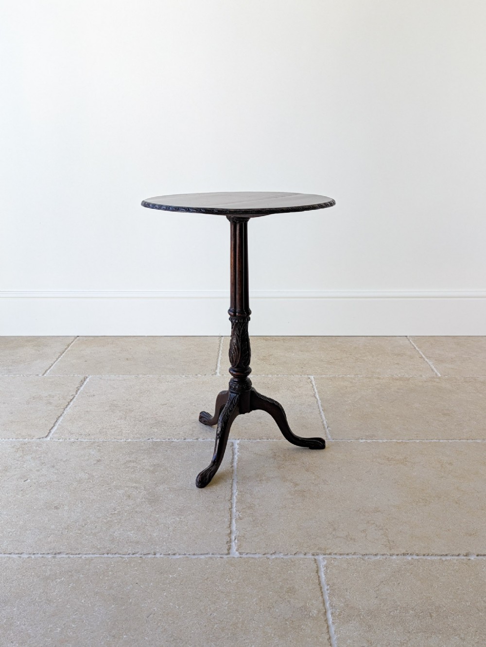 A dark mahogany tripod wine table with a circular top, turned carved column stem, and three cabriole legs.
