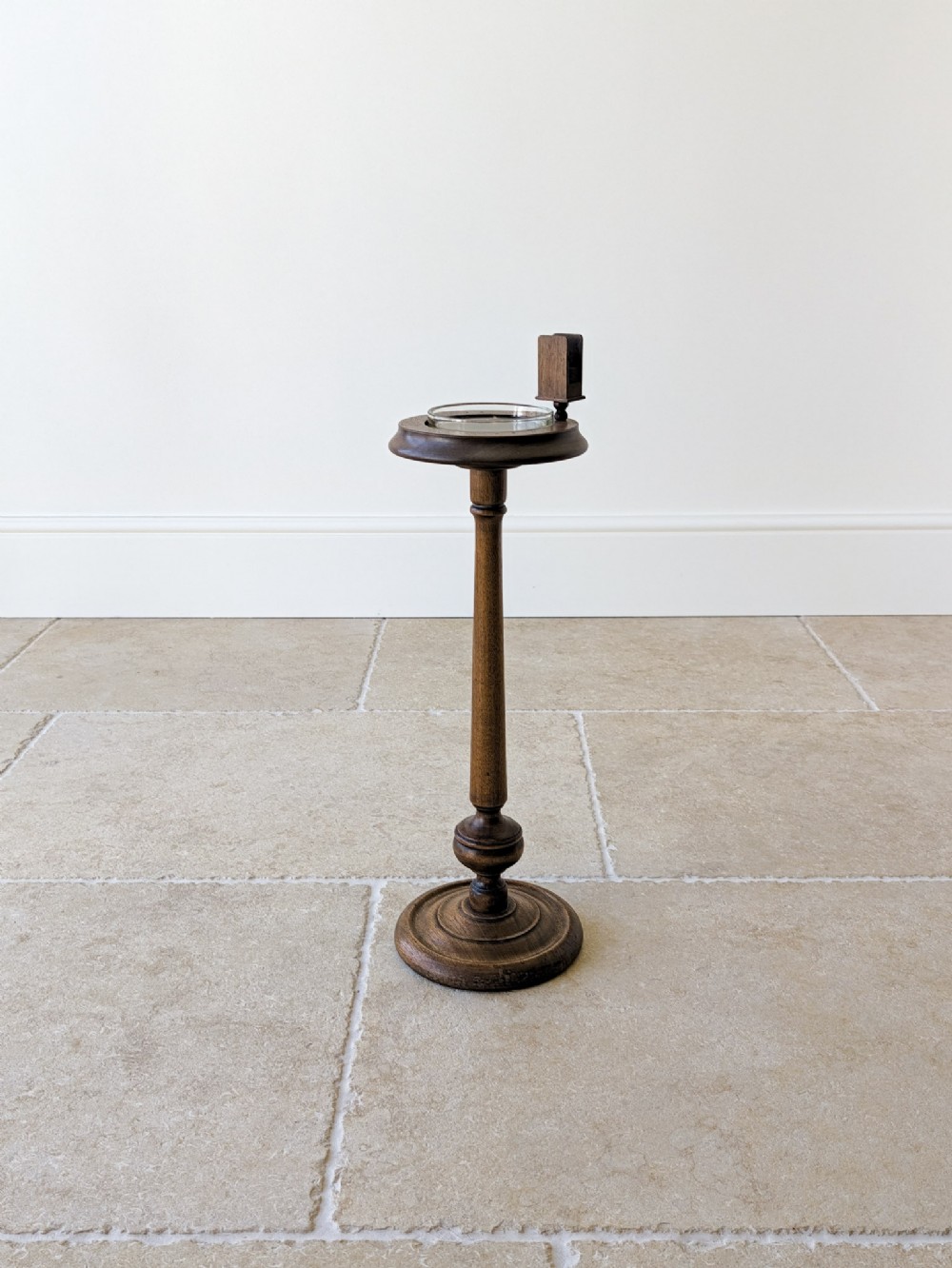 An Edwardian mahogany floor-standing smoking stand featuring a turned central column, a circular stepped base, a glass tray insert, and a mounted timber matchbox holder.