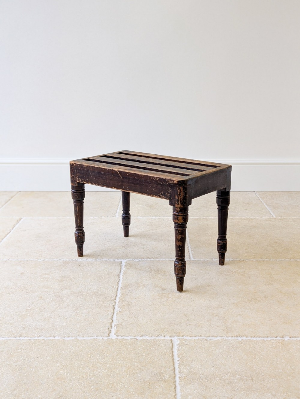 A Victorian dark brown beech wooden luggage stand featuring a slatted top and turned legs.