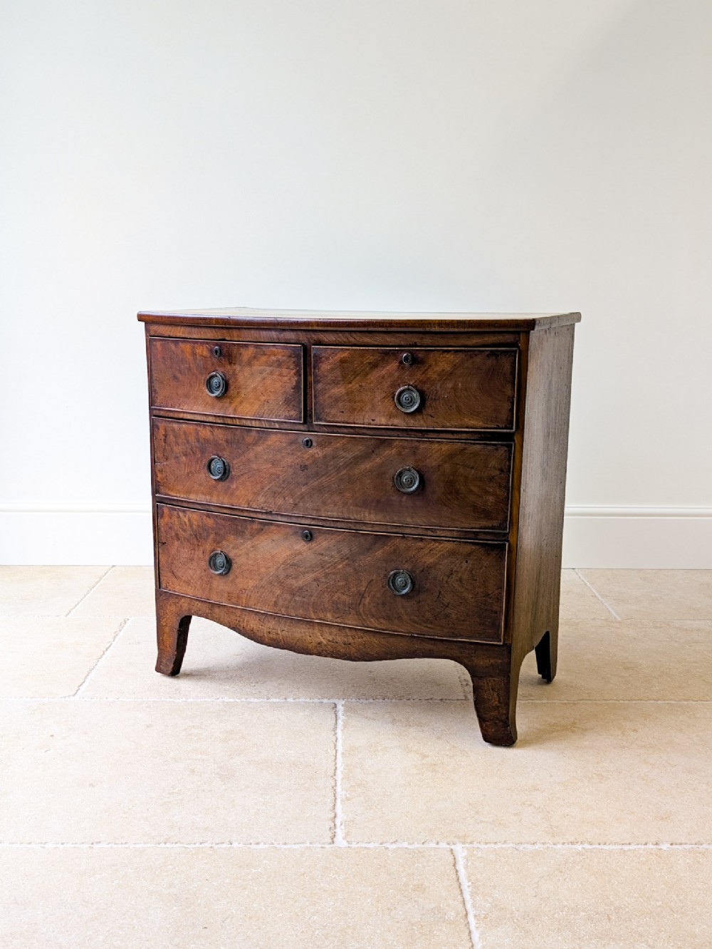 An antique Georgian flame mahogany bowfront chest of drawers featuring two short over two long drawers on splayed bracket feet.