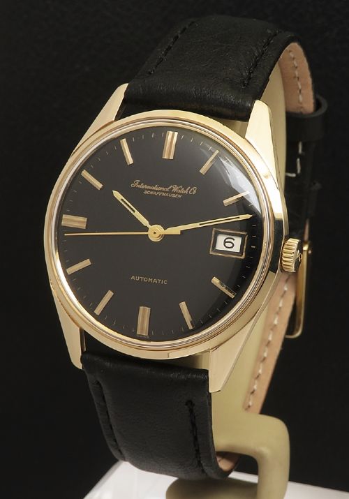 fig 1. A vintage 1960s IWC wristwatch featuring a solid gold case, a black dial with gold baton hour markers, and a black leather strap.