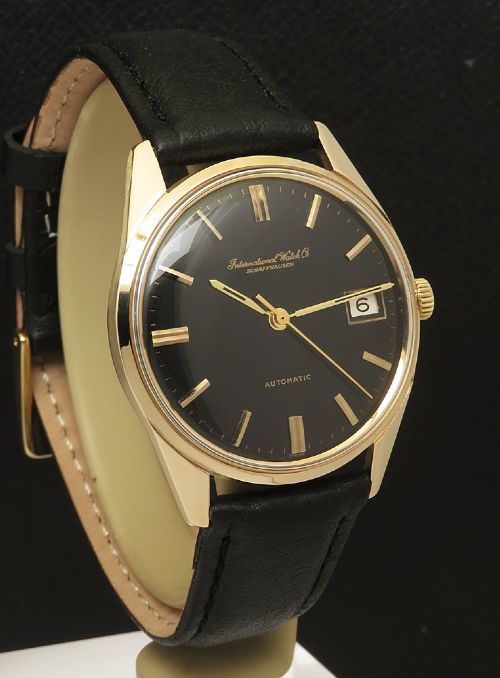fig 3. A vintage 1960s IWC wristwatch featuring a solid gold case, a black dial with gold baton hour markers, and a black leather strap.