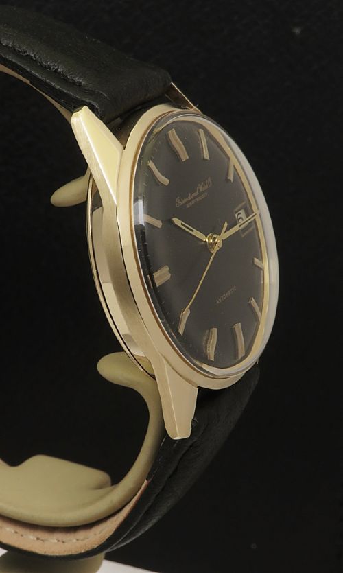 fig 4. A vintage 1960s IWC wristwatch featuring a solid gold case, a black dial with gold baton hour markers, and a black leather strap.