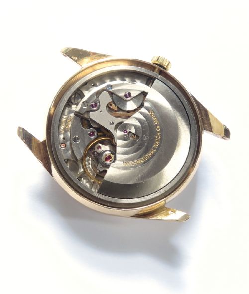fig 6. A vintage 1960s IWC wristwatch featuring a solid gold case, a black dial with gold baton hour markers, and a black leather strap.