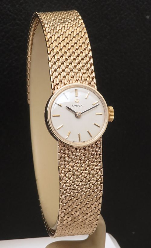 fig 3. A 1967 Omega ladies wristwatch featuring a round white dial with gold baton markers and an integrated woven 9ct gold bracelet.
