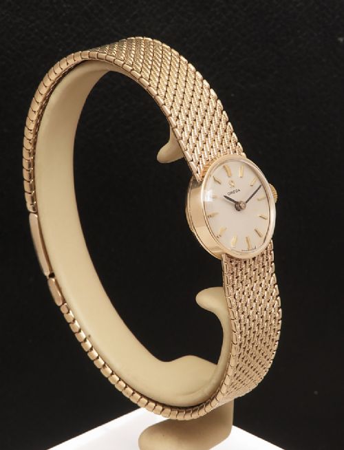 fig 4. A 1967 Omega ladies wristwatch featuring a round white dial with gold baton markers and an integrated woven 9ct gold bracelet.