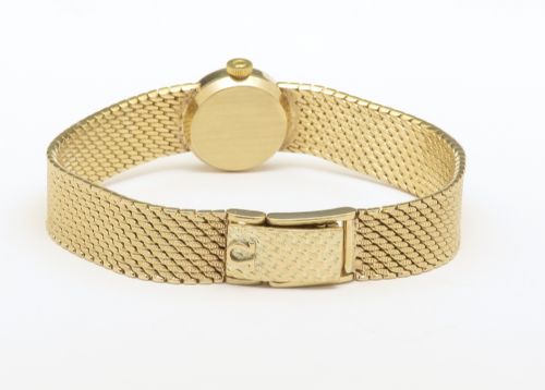 fig 5. A 1967 Omega ladies wristwatch featuring a round white dial with gold baton markers and an integrated woven 9ct gold bracelet.