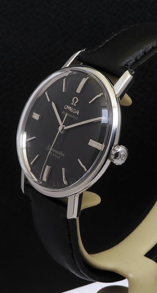 fig 2. A vintage Omega Seamaster DeVille wristwatch featuring a round stainless steel case, a black dial with silver baton hour markers, and a stitched black leather strap.