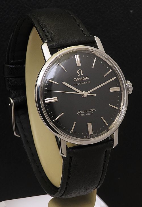 fig 3. A vintage Omega Seamaster DeVille wristwatch featuring a round stainless steel case, a black dial with silver baton hour markers, and a stitched black leather strap.