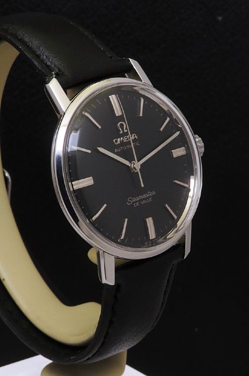 fig 4. A vintage Omega Seamaster DeVille wristwatch featuring a round stainless steel case, a black dial with silver baton hour markers, and a stitched black leather strap.