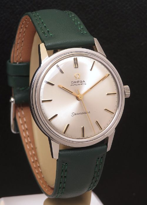 fig 3. A 1967 stainless steel Omega Seamaster Automatic wristwatch with a silver dial, gold baton hour markers, and a dark green leather strap.