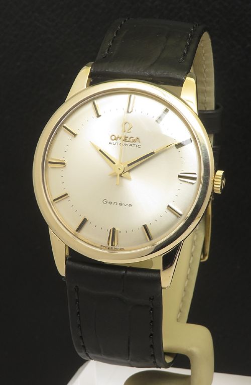 fig 1. A 1967 Omega Geneve automatic wristwatch featuring a circular solid 9ct gold case, a silvered sunburst dial with gold baton hour markers, and a black leather strap.