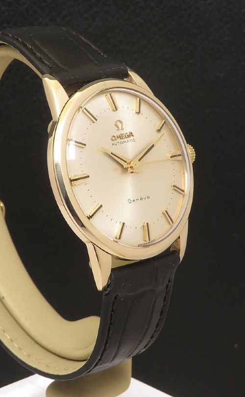fig 4. A 1967 Omega Geneve automatic wristwatch featuring a circular solid 9ct gold case, a silvered sunburst dial with gold baton hour markers, and a black leather strap.