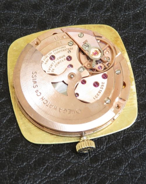 fig 2. A 1968 Omega Constellation Deluxe wristwatch featuring a cushion-shaped 18ct gold case, brushed champagne dial, baton indices, and a black textured leather strap.
