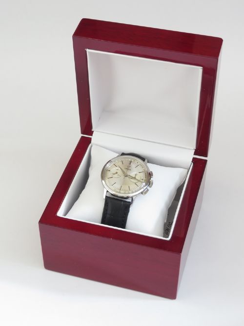 A 1963 stainless steel Omega chronograph wristwatch featuring a silver dial with two sub-dials and a black leather strap. View IX