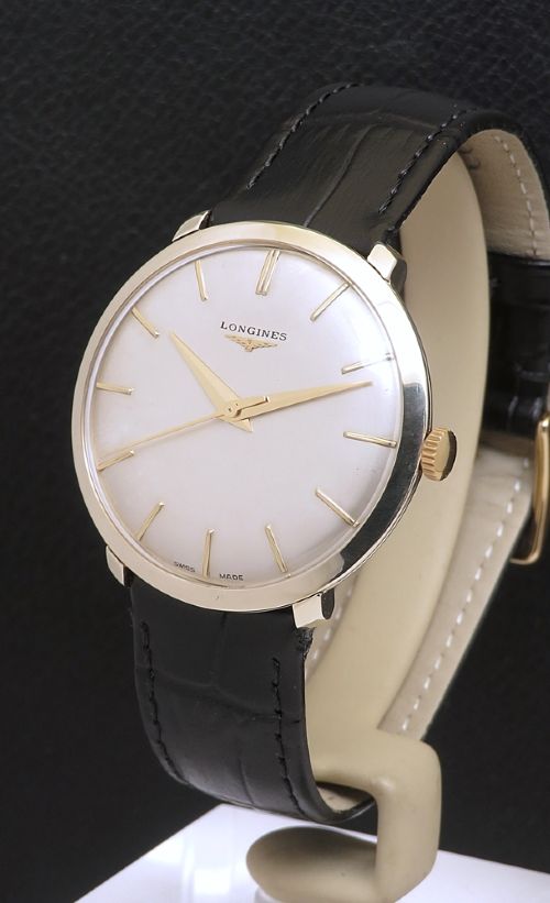 fig 1. A 1960 vintage Longines wristwatch featuring a round solid gold case, silver dial with gold markers, and a black leather strap.