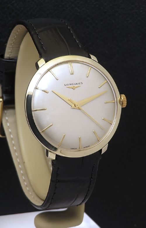 fig 2. A 1960 vintage Longines wristwatch featuring a round solid gold case, silver dial with gold markers, and a black leather strap.