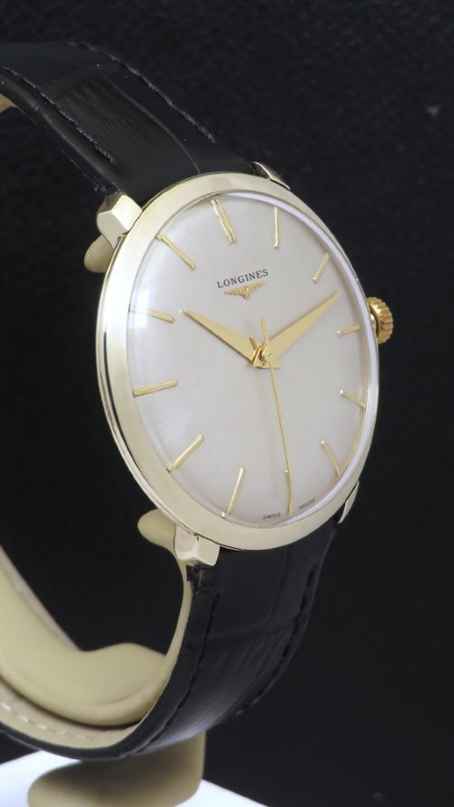 fig 3. A 1960 vintage Longines wristwatch featuring a round solid gold case, silver dial with gold markers, and a black leather strap.