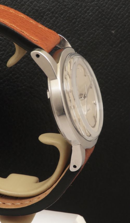 fig 3. A 1950 vintage Omega Seamaster automatic wristwatch featuring a stainless steel case, cream dial with silver index markers, and a stitched tan leather strap.