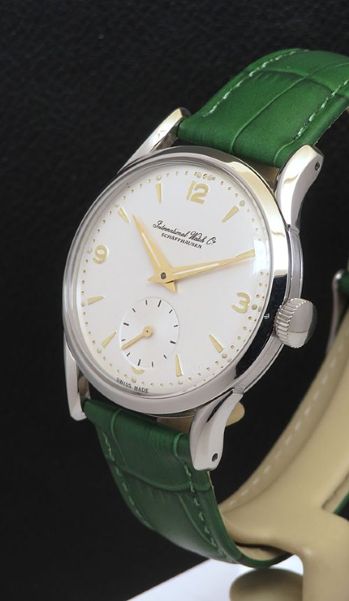 fig 1. A vintage Swiss wristwatch featuring a stainless steel case, white dial with gold-tone markers, sub-seconds subdial, and a green leather strap.