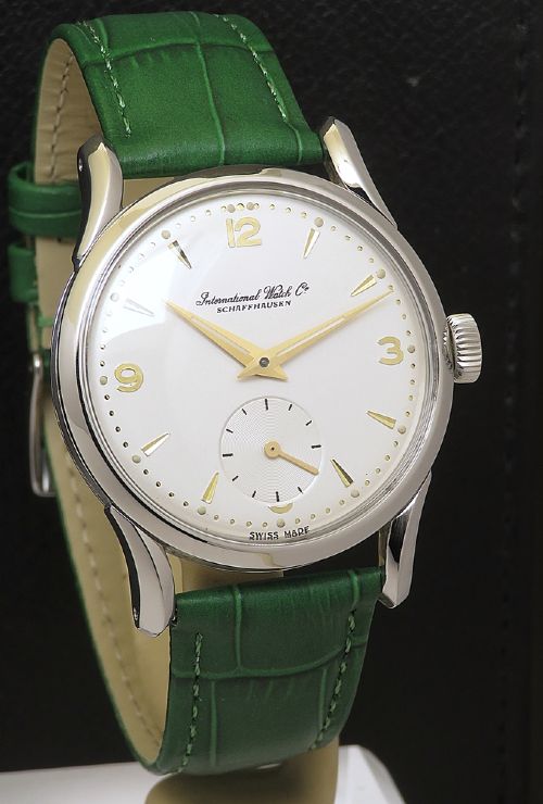 fig 2. A vintage Swiss wristwatch featuring a stainless steel case, white dial with gold-tone markers, sub-seconds subdial, and a green leather strap.