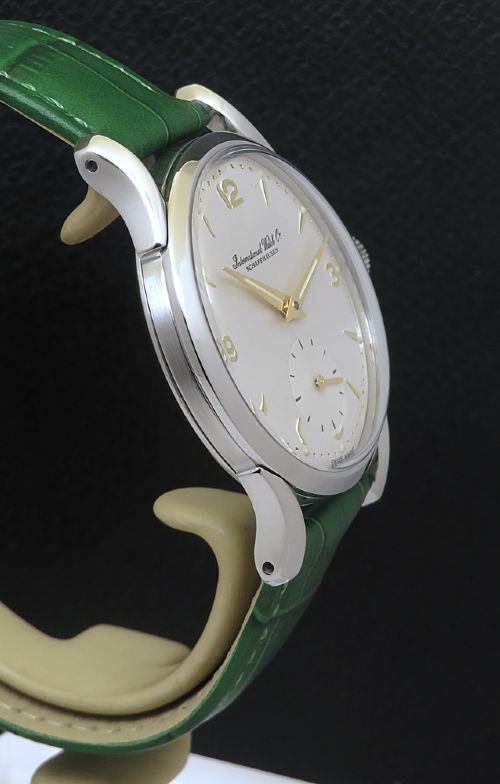 fig 3. A vintage Swiss wristwatch featuring a stainless steel case, white dial with gold-tone markers, sub-seconds subdial, and a green leather strap.