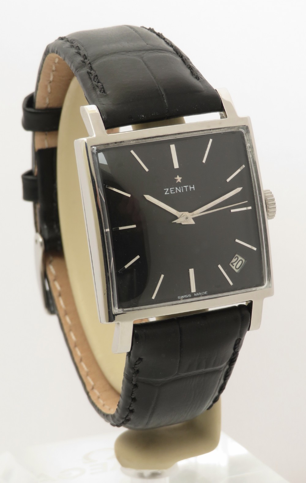 A vintage 1960s Zenith square wristwatch with a black dial, silver baton indices, date window, and a black leather strap.