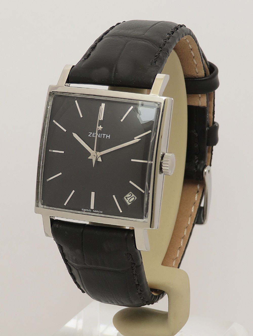 A vintage 1960s Zenith square wristwatch with a black dial, silver baton indices, date window, and a black leather strap. View II