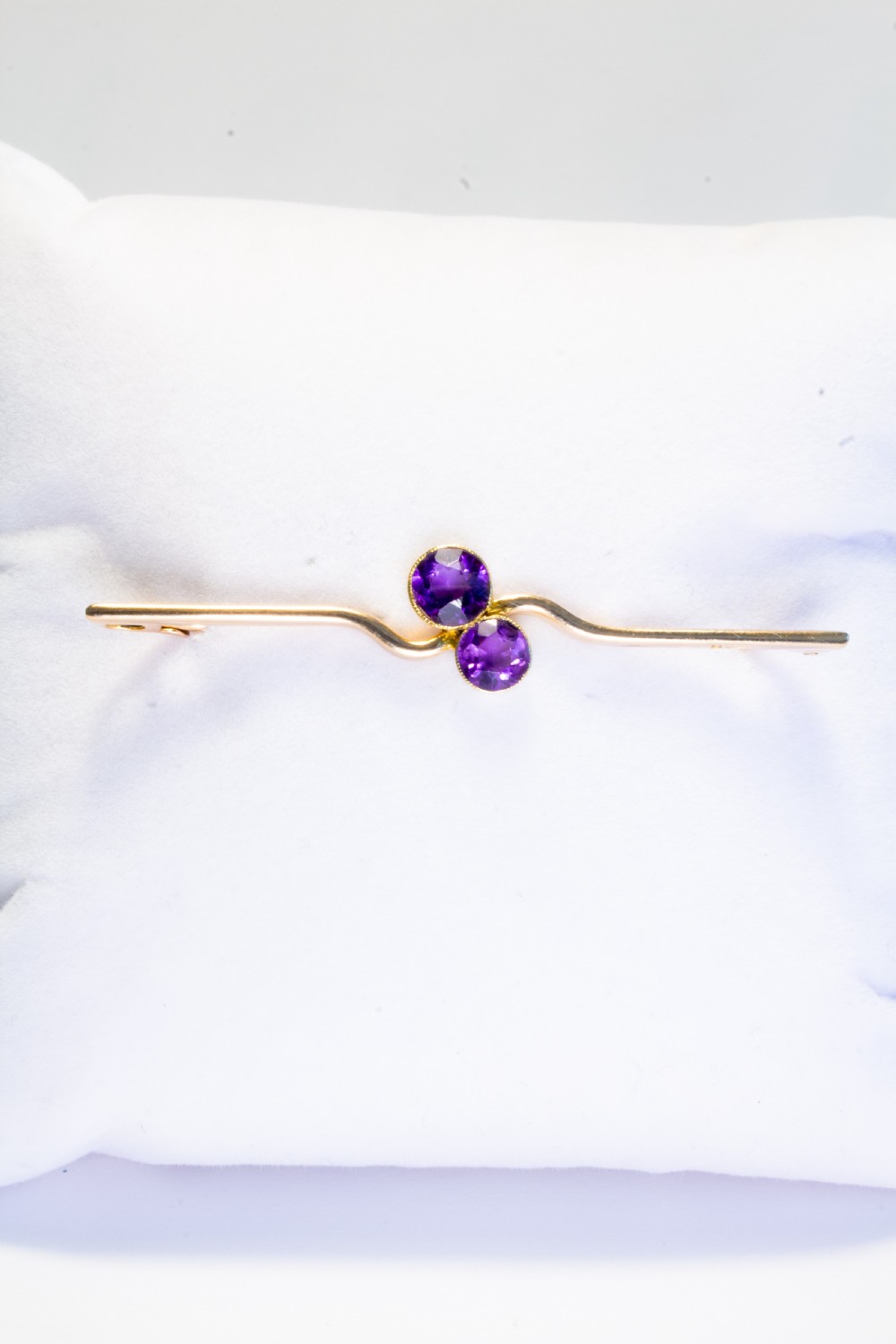 An early 20th century 9ct gold bar brooch featuring a central curved design set with two round-cut purple amethysts. View III