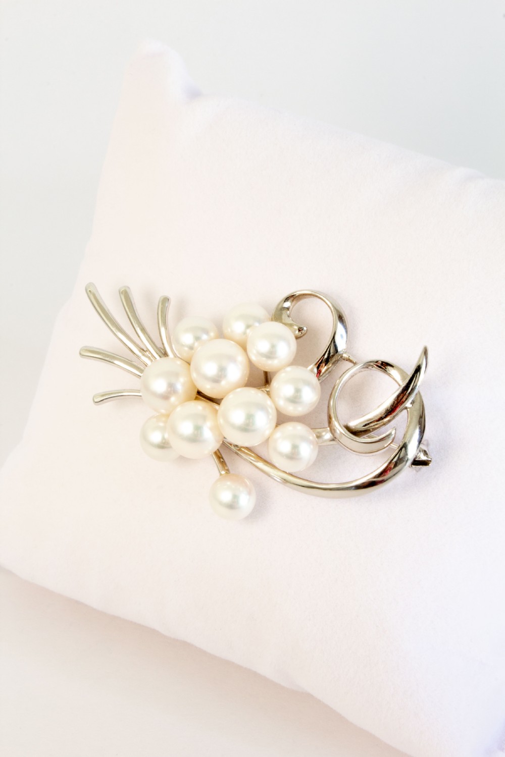 A sterling silver brooch featuring a cluster of round white cultured pearls framed by fluid, polished metal curves and ribbon flourishes. View III