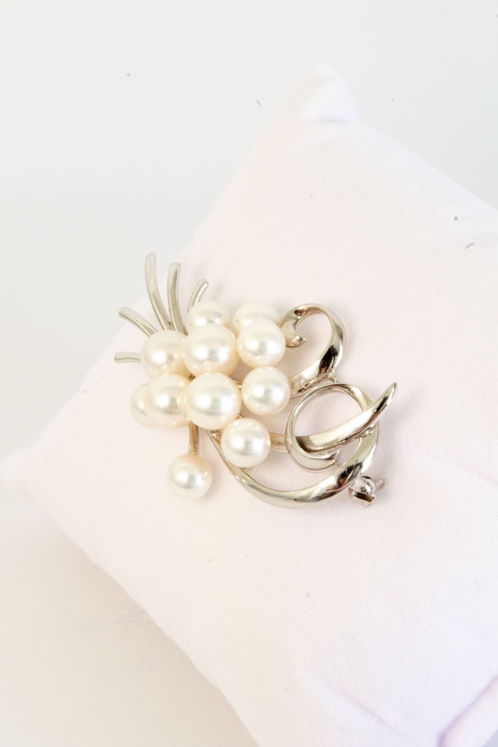 A sterling silver brooch featuring a cluster of round white cultured pearls framed by fluid, polished metal curves and ribbon flourishes. View IV