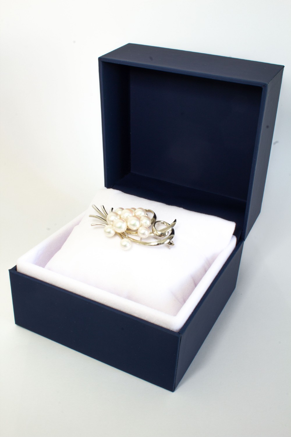A sterling silver brooch featuring a cluster of round white cultured pearls framed by fluid, polished metal curves and ribbon flourishes. View VI