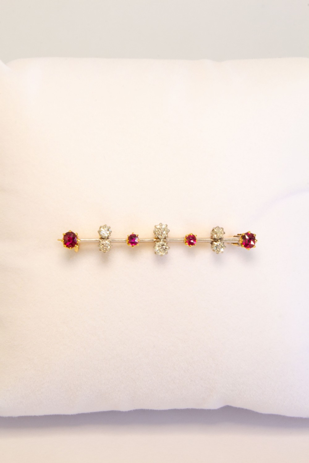 An early 20th-century bar brooch in gold set with an alternating linear row of red rubies and white diamonds in claw settings. View III