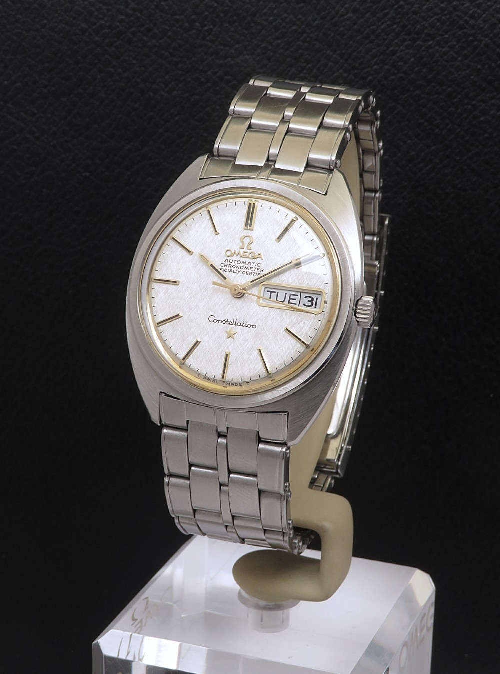 A stainless steel Omega Constellation wristwatch featuring a textured silver dial, day-date window, and integrated steel bracelet.