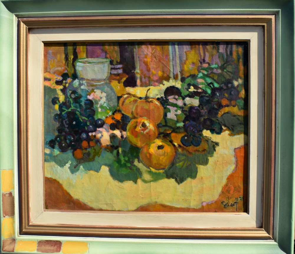 A framed post-impressionist still life oil painting depicting a glass jug, dark grapes, and yellow fruit on a draped surface.