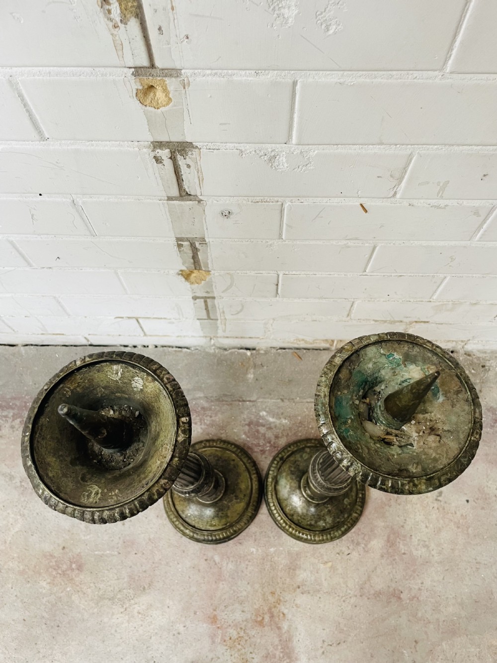 A pair of tall aged brass pricket candlesticks featuring fluted central columns, flared drip trays, top candle spikes, and circular patterned bases. View III
