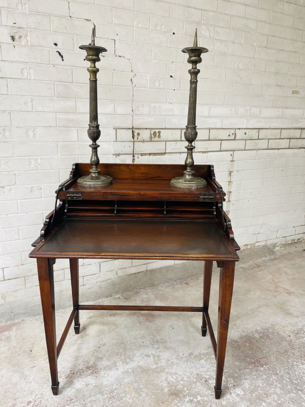 A pair of tall aged brass pricket candlesticks featuring fluted central columns, flared drip trays, top candle spikes, and circular patterned bases. View X