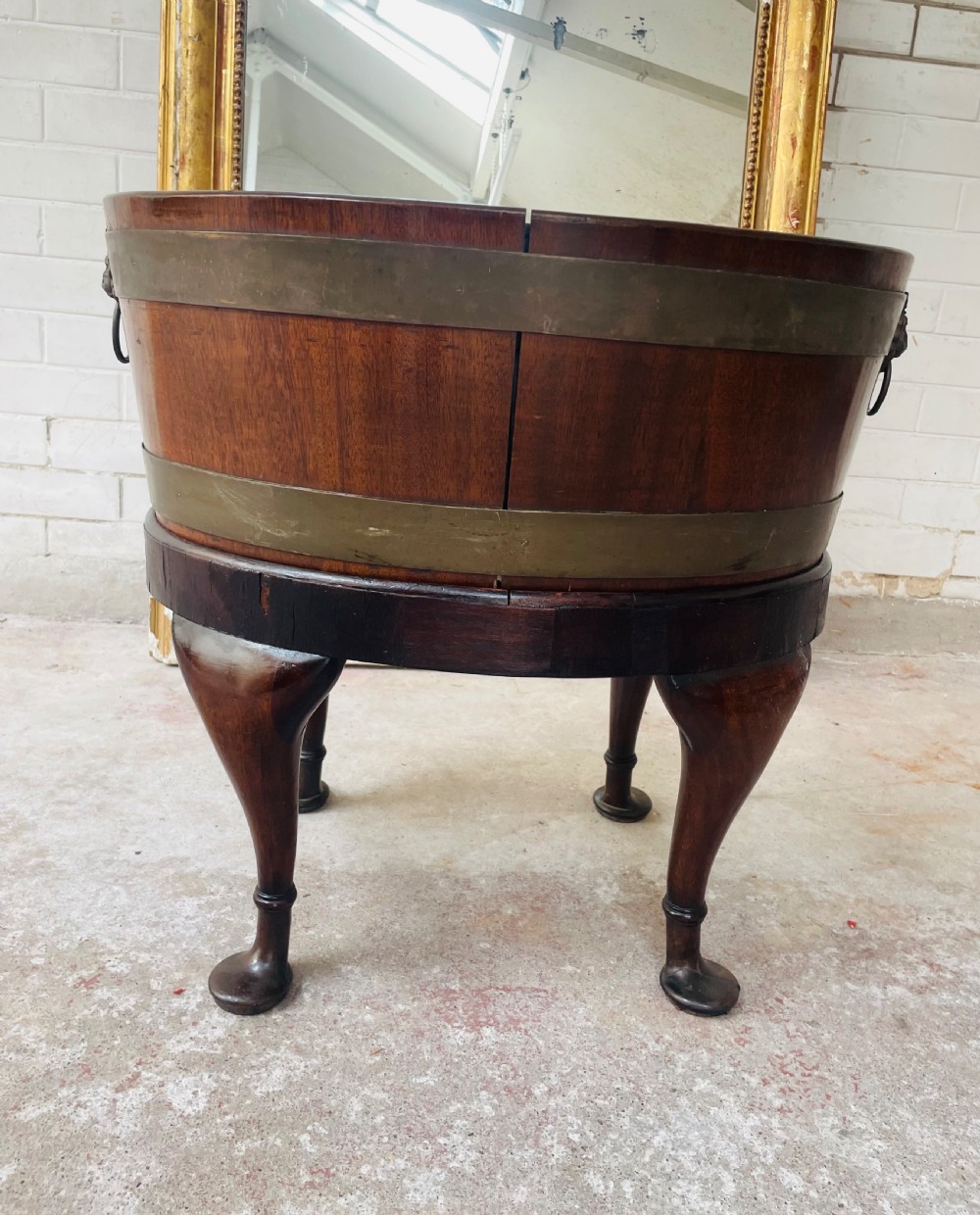 An oval brass-bound mahogany wine cooler on a stand with cabriole legs, pad feet, and lion mask handles. View III