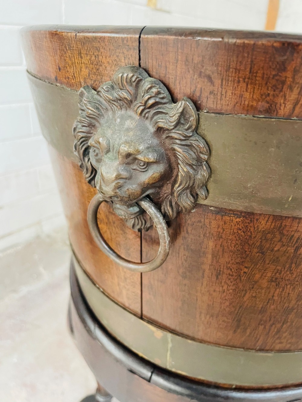 An oval brass-bound mahogany wine cooler on a stand with cabriole legs, pad feet, and lion mask handles. View VII