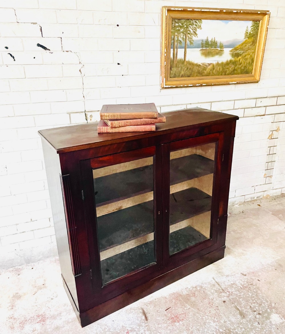 A low dark mahogany glazed bookcase featuring two glass panel doors, fluted side pilasters, and an integrated plinth base. View II