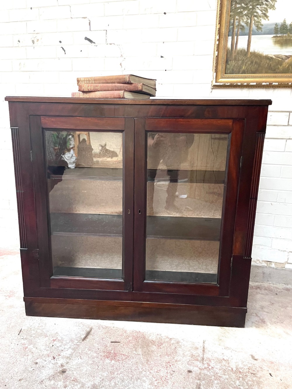 A low dark mahogany glazed bookcase featuring two glass panel doors, fluted side pilasters, and an integrated plinth base. View V