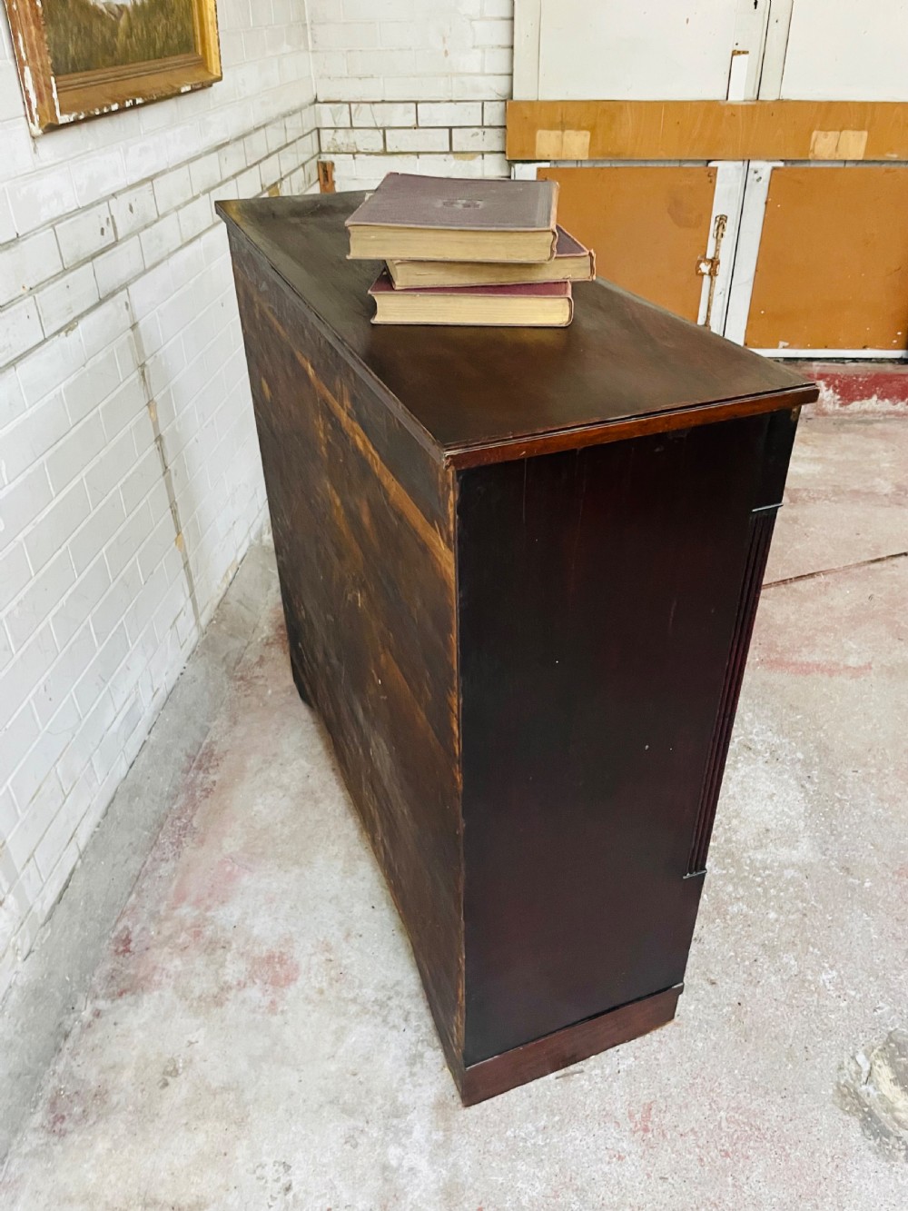 A low dark mahogany glazed bookcase featuring two glass panel doors, fluted side pilasters, and an integrated plinth base. View IX
