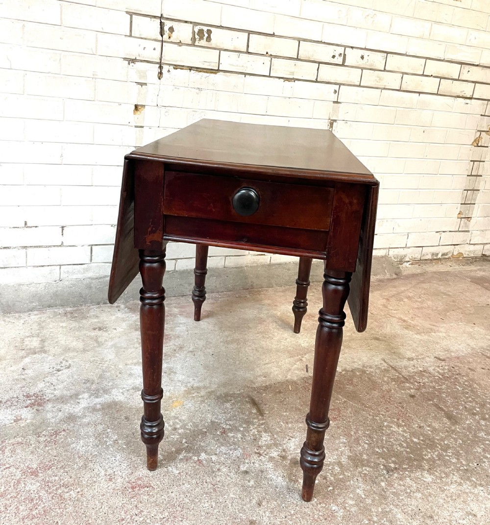 A Victorian mahogany drop-leaf table with extended side flaps, a central drawer with a turned black knob, and four turned legs. View II