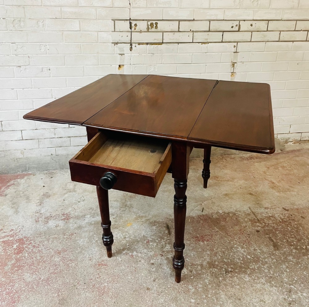 A Victorian mahogany drop-leaf table with extended side flaps, a central drawer with a turned black knob, and four turned legs. View VI