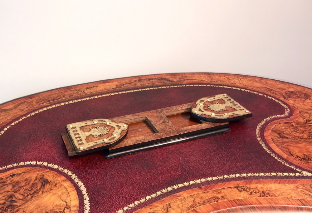 An antique burr walnut adjustable book slide featuring decorative brass strapwork mounts with rounded ends.