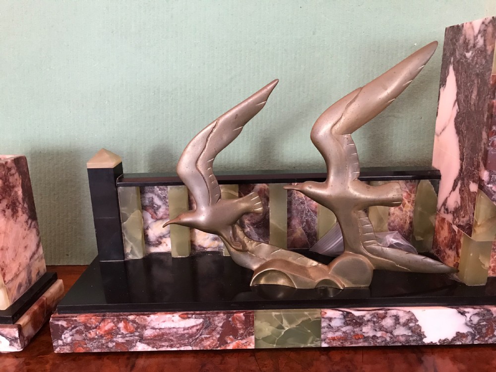 An Art Deco three-piece marble clock garniture set featuring a central clock with cast bronze birds in flight and two matching square side urns. View III