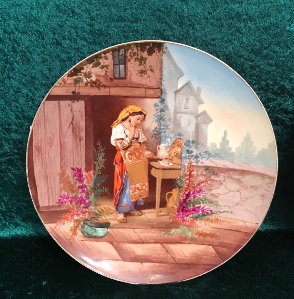 A pair of circular ceramic wall plaques depicting hand-painted European rustic genre scenes with figures in traditional dress against village backdrops. View IV